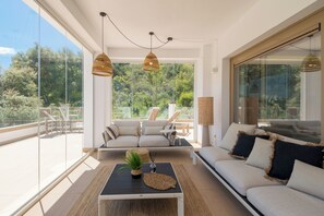 A modern living room with a sofa, a coffee table, and a view of the outdoors. - Stylish 3-bed Apt on La Cala Golf 15th Hole View (Mijas)