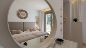 Ein modernes Schlafzimmer mit einem großen Spiegel, einem Bett mit vielen Kissen, einem Nachttisch und einem Kleiderschrank.