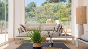 Ein modernes Wohnzimmer mit Sofa, Couchtisch, Lampe und Blick ins Freie.