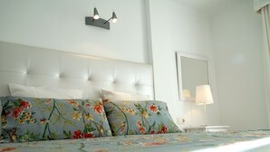 A bedroom with a tufted headboard, floral bedspread, and a bedside lamp. - Exclusive holiday apartment in Colonia Sant Jordi for max. 4 people (Colonia Sant Jordi)