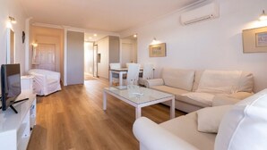 A modern living room with a sofa, a glass coffee table, and a dining area with chairs. - Exclusive holiday apartment in Colonia Sant Jordi for max. 4 people (Colonia Sant Jordi)