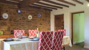 A dining area with a stone wall, wooden beams, and a table set for four. - Set in the picturesque border town of Montgomery, close to all town amenities. (Montgomery, near Welshpool)