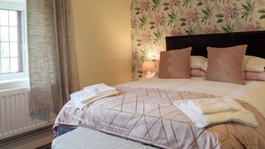 A hotel room with a bed, curtains, a floral wallpaper, and a bedside lamp. - Set in the picturesque border town of Montgomery, close to all town amenities. (Montgomery, near Welshpool)