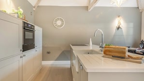 A modern kitchen with a built-in oven, a sink, and a clock on the wall. - 2 bedroom accommodation in Northrepps (Northrepps)