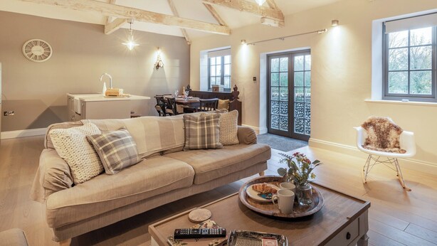 A cozy living room with a large sofa, a coffee table with a tray of food, and a fireplace. - 2 bedroom accommodation in Northrepps (Northrepps)