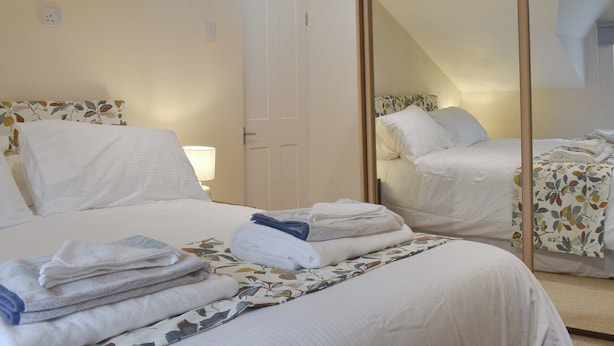 A bedroom with a bed, a mirror, and a door. - The Coach House Halifax (Halifax)
