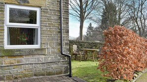 A stone building with a window, a brick pathway, and a bush with autumn leaves. - The Coach House Halifax (Halifax)