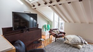 Un salon moderne avec un téléviseur à écran plat, un fauteuil en cuir, une petite table ronde et un tapis moelleux.