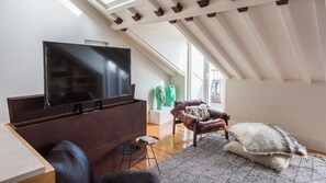 A modern living room with a flat-screen TV, a leather armchair, a small round table, and a fluffy rug.