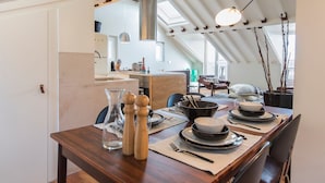 Un coin repas avec une table en bois mise pour quatre personnes, comprenant des assiettes, des bols et des couverts.
