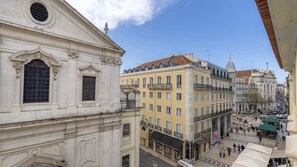 A historic building with classical architecture, a bustling street below, and a clear blue sky.