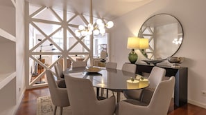 A modern dining area with a round table, four chairs, a green lamp, and a large mirror.