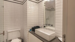 A modern bathroom with white subway tiles, a large rectangular sink, and a glass-enclosed shower.