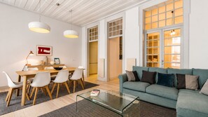A modern living room with a glass coffee table, a sofa, and a dining area with chairs and a table.