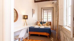 A bedroom with a bed, a desk, a chair, a lamp, and a window. - Dirk Apartment - Almada 3º T by LovelyStay (Porto)