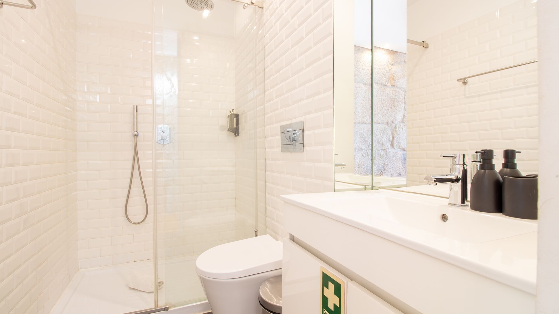 Een moderne badkamer met een douchecabine van glas, een wit toilet en een wastafel met spiegel.