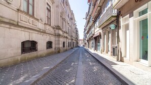 Une rue pavée bordée de bâtiments historiques, où se côtoient différents styles architecturaux, et un ciel dégagé au-dessus.
