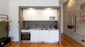 A compact kitchen with white cabinets, a built-in microwave, a sink, and a stove. - Allderman Apartment - Almada 3º F by LovelyStay (Porto)