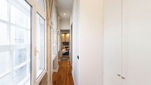 A narrow hallway with large windows on one side and a door at the end.