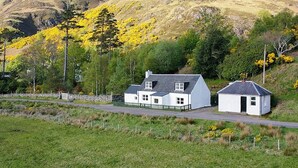 A rural setting with a white house, a smaller white structure, and a mountain backdrop. - 3 bedroom accommodation in Arnisdale, Kyle of Lochalsh (Arnisdale, Kyle of Lochalsh)