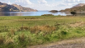 A rural landscape with a lake, grassy fields, and mountains in the background. - 3 bedroom accommodation in Arnisdale, Kyle of Lochalsh (Arnisdale, Kyle of Lochalsh)