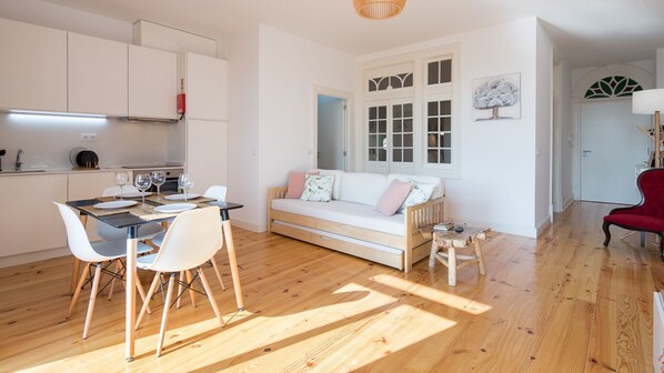 A modern apartment with a dining area, a sofa, and a red chair.