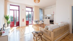 Een modern appartement met houten vloer, een eethoek met tafel en stoelen, een keuken met witte kasten en een balkon met rode deuren.