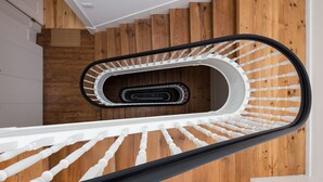 Een moderne spiraaltrap met houten treden en witte spijlen.