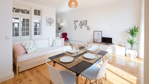 Een moderne woonkamer met een eethoek, witte meubels en een groot raam.