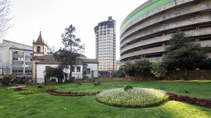Um parque com gramados bem cuidados, canteiros de flores e uma grande estrutura de estacionamento.