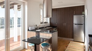 Uma cozinha moderna com uma ilha central, eletrodomésticos de aço inoxidável e vista para a cidade através de grandes janelas.