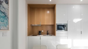 A modern kitchen with wooden cabinets, a built-in microwave, and a coffee maker. - Wohaza Flat w/ Parking by LovelyStay (Porto)