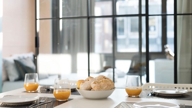A breakfast setting with a bowl of pastries and two glasses of orange juice on a table. - Wohaza Flat w/ Parking by LovelyStay (Porto)