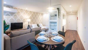 Ein modernes Wohnzimmer mit Sofa, Fernseher und Essbereich, gedeckt für eine Mahlzeit.