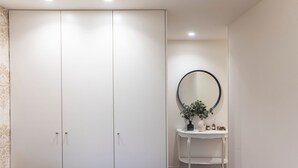 Ein Schlafzimmer mit einem Kleiderschrank, einem Nachttisch mit Spiegel und einer kleinen Pflanze.