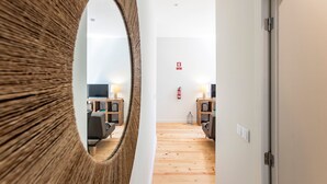 Un pasillo con suelo de madera, un espejo y un extintor en la pared.