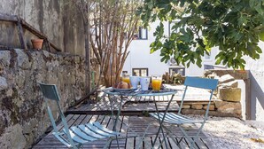 Une terrasse extérieure avec une table et des chaises, un mur en pierre et un arbre.