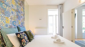 A hotel room with a bed, pillows, a view of the outdoors, and a door leading to a balcony. - Porto Flores Plaza by LovelyStay (Porto)