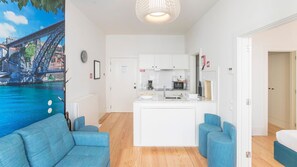 A modern apartment with a kitchen, a dining area, and a living room with a sofa and armchairs.