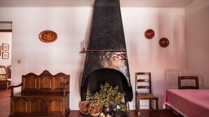 Una habitación con chimenea tradicional, muebles de madera y placas decorativas en las paredes.