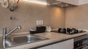 Eine moderne Küche mit Spüle aus Edelstahl, einem Gasherd und einer schwarzen Box auf der Arbeitsfläche.