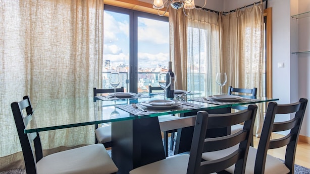 Un comedor con una mesa de vidrio, sillas y una botella de vino.