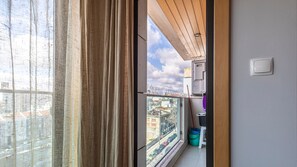 Une vue depuis un balcon, avec un ciel dégagé, une rue en contrebas et un bâtiment avec un toit rouge.