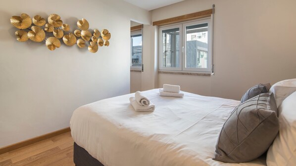A bedroom with a large bed, a window, and a wall decoration.
