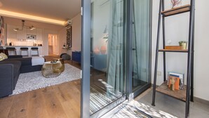 Un salon moderne avec un canapé, une table basse et une porte vitrée donnant sur la cuisine.