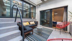 Un espace de vie extérieur moderne comprenant un canapé, deux fauteuils et un escalier.