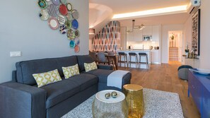 A modern living room with a grey sofa, patterned cushions, a coffee table, and a decorative wall with various plates.