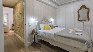 A bedroom with a bed, bedside tables, a mirror, and a view of the bathroom.