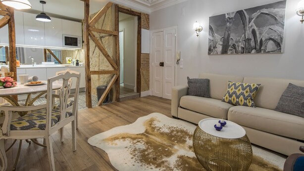 A modern living room with a sofa, a round coffee table, and a dining area with a table and chairs.