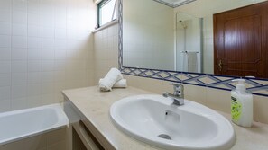 Ein Badezimmer mit einem weißen Waschbecken, einem Spiegel und einer Dusche.